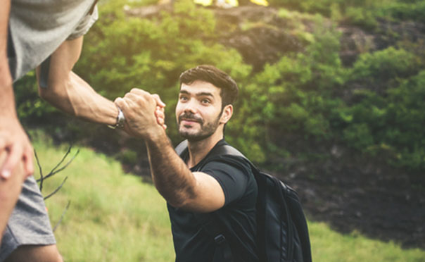 Young man being helped hiking