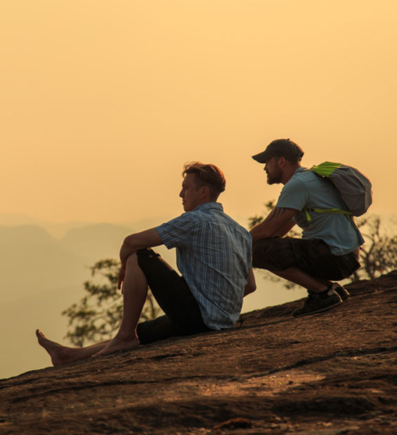 Two men sitting on a rock in the sunset